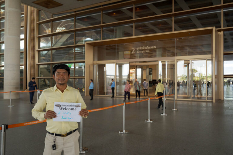 Driver holding name sign at KTI Phnom Penh International airport wating in arrivals area for guests